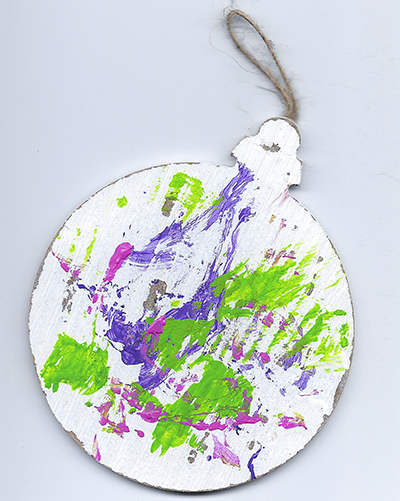An abstract acrylic painting on a wooden ornament with purple, green, and pink streaks and dots