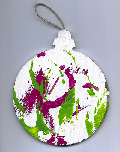 An abstract acrylic painting on a wooden ornament with red and green streaks and dots